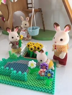 some small toy animals are standing on a table with flowers and legos in front of them