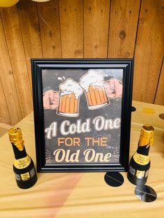 two bottles of beer sitting next to a sign that says, a cold one for the old one