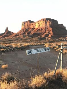 a no trespassing sign is posted on a barbed wire fence in the desert