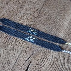 two blue bracelets sitting on top of a piece of wood next to an arrow