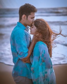 a man and woman standing next to each other on the beach