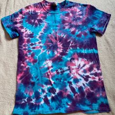 a purple and blue tie - dyed shirt laying on top of a bed