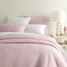 a bed with pink bedspread and white pillows