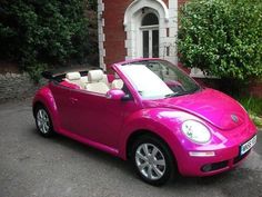 a pink convertible car parked in front of a house