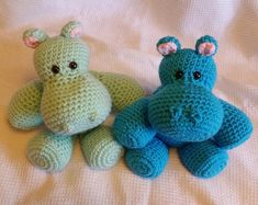 two crocheted stuffed animals sitting next to each other on a white sheet,