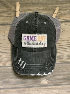 "It's GAME DAY! Sport your favorite hat while supporting your favorite team! This hat is perfect to throw your hair up in this criss cross ponytail hat! Unisex distressed gray trucker hat with gray adjustable(velcro) mesh backing. Patch is handmade and says \"Game Day is the best day\" in black, purple and gold. Can put any patch from our shop on this hat! Put in notes to seller." Game Day Hat For Baseball Season, Adjustable Visor Snapback Hat For Game Day, Fan Gear Visor Hat, One Size Fits Most, Adjustable Hats For Fan Merchandise With Team Spirit, Adjustable Gray Hat For Sports Events, Adjustable Sports Fan Hat For Fan Merchandise, Game Day Adjustable Snapback Hat With Curved Brim, Adjustable Fan Merchandise Hat, Game Day Team-colored Cap