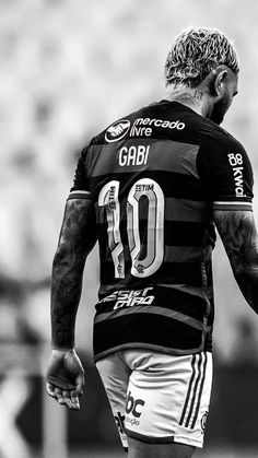 a black and white photo of a man with tattoos on his arm, holding a soccer ball