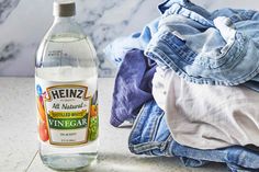 a bottle of vinegar next to clothes on a counter