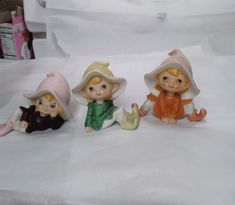 three little figurines sitting on top of a white sheet