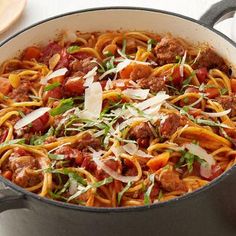 a large pot filled with pasta and meat on top of a table next to vegetables