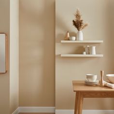 two white shelves with dishes and vases on them in a neutral living room setting