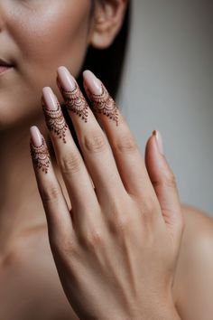 a woman's hands with hennap on her fingers and nail polish in front of her face