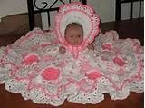 a baby in a pink and white crocheted blanket on top of a table