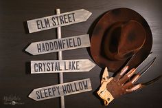 a cowboy hat, gloves and other items are placed on a signpost that says elm street, haddonfield, crystal lake, sleepy hollow