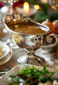 a silver bowl filled with soup sitting on top of a table next to other dishes