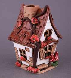 a ceramic house with red flowers on the roof