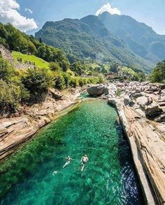 a person swimming in the water with mountains in the background