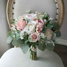 a bridal bouquet sitting on top of a chair with greenery and flowers in it