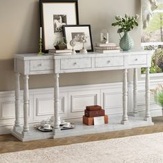 a white console table with two pictures on top and coffee cups in front of it