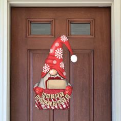 a christmas door hanger with an elf's hat hanging on the front door