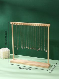 a wooden jewelry rack with beads hanging from it's sides and a white cube next to it