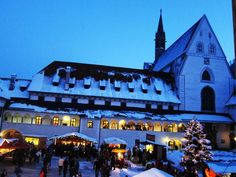 people are walking around in front of a large building with christmas decorations on the outside