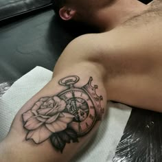 a man with a tattoo on his arm has a clock and rose tattooed on it