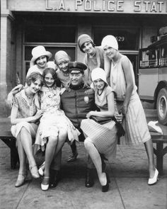 a group of women sitting on top of a bench in front of a police station