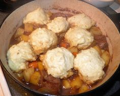 a pot filled with stew and dumplings on top of a stove