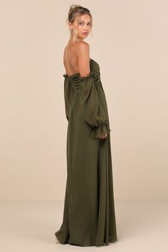 a woman in a green dress is looking back at the camera and has her hands on her hips