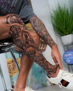 a man sitting on top of a stool with his legs covered in tattoos and shoes