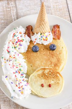 pancakes with whipped cream, bacon, and blueberries are on a plate