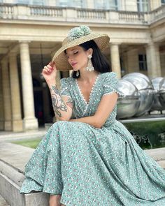 a woman in a dress and hat sitting on a ledge