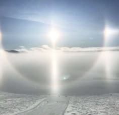 the sun shines through two circles in the sky over snow covered ground and mountains