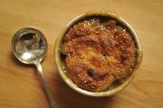 a small bowl with some food in it next to a spoon on a wooden table