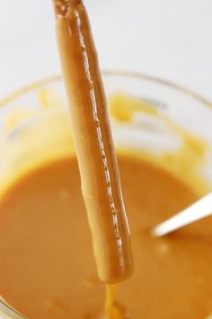 a spoon is being used to stir peanut butter in a glass bowl with caramel sauce