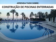 an empty swimming pool with lounge chairs and palm trees