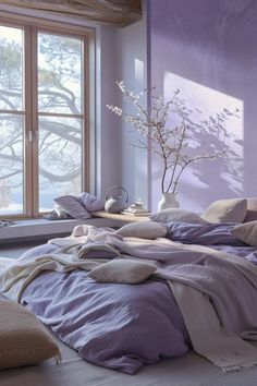 a bedroom with purple walls and bedding in front of a large window that looks out onto the snow covered trees