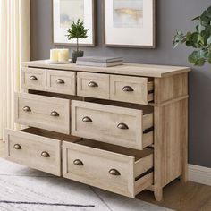 a dresser with drawers and two pictures on the wall