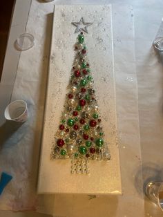 a christmas tree made out of glass beads is displayed on a table with other items