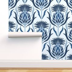 a blue and white wallpaper with an artichoke pattern on the wall next to a roll of toilet paper