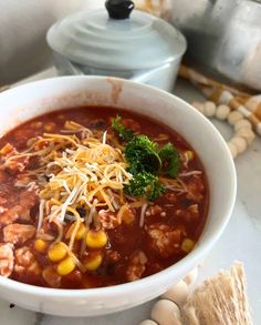 a white bowl filled with chili, corn and cheese