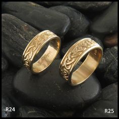 two gold wedding rings sitting on top of rocks