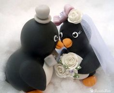 two black and white birds with flowers in their beaks on the snow covered ground