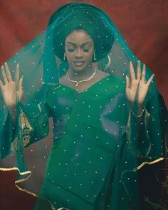 a woman wearing a green veil and holding her hands up