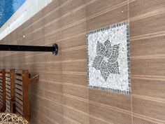 a wooden bench sitting next to a wall with a mosaic tile design on it's side