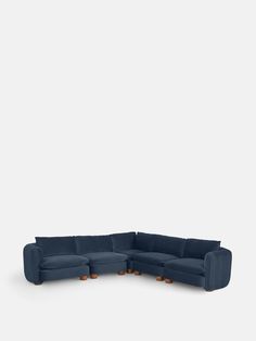 a blue sectional couch with wooden legs and footrests, on a white background