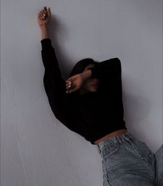 a woman leaning up against a wall with her hands in the air