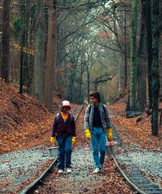 two people walking on train tracks in the woods