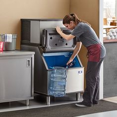 a woman opening up a cooler in a kitchen